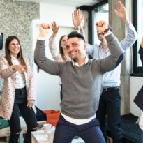 Menschen tanzen im Büro - Arme oben und Lachen